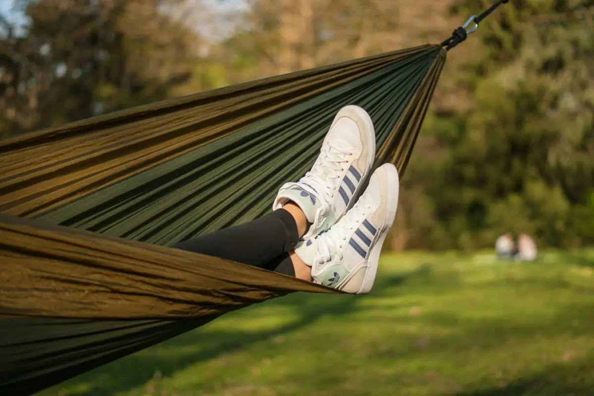 A green hammock with feet sticking out