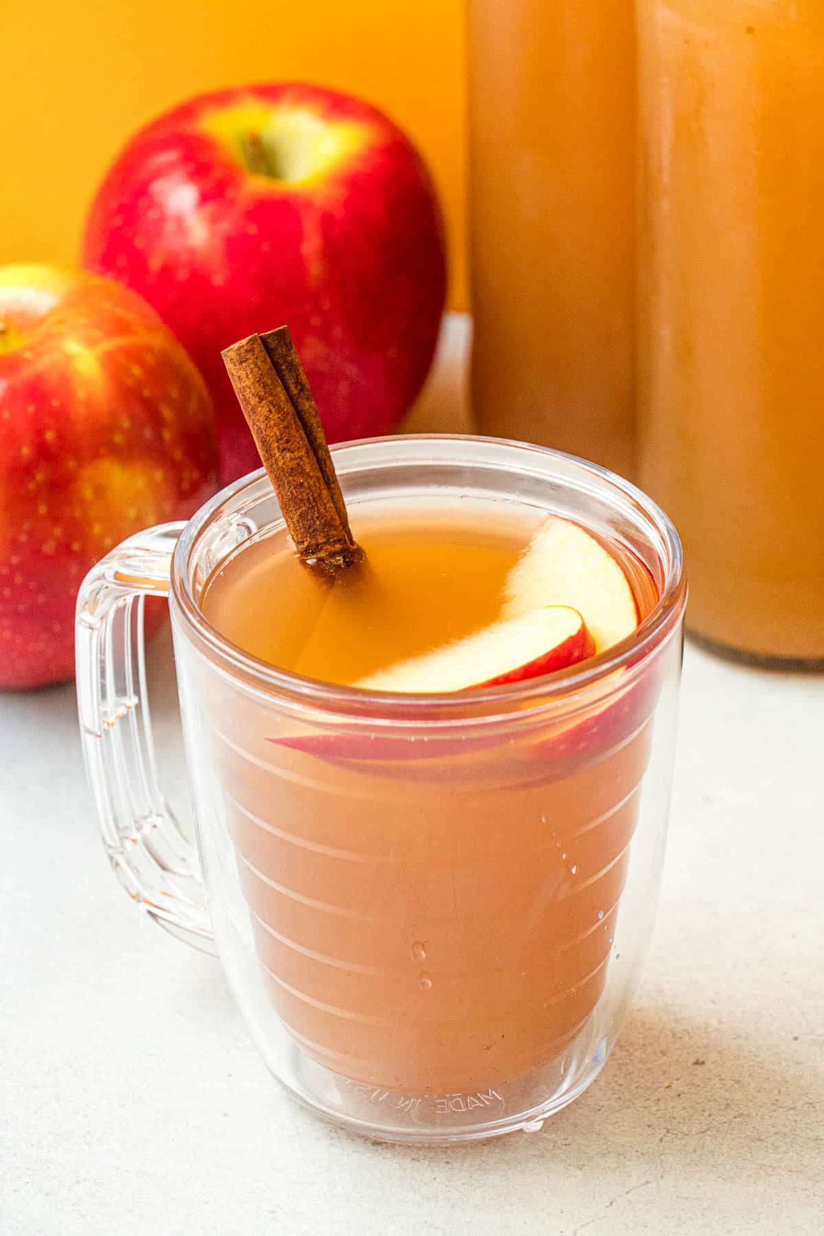 Homemade apple cider in a mug, garnished with a cinnamon stick.