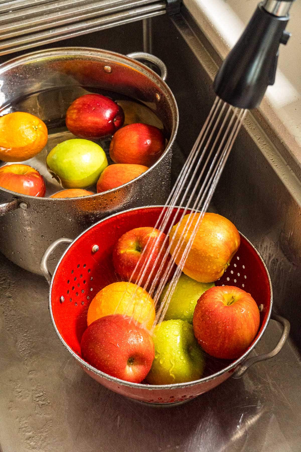Washing apples in a red colander.