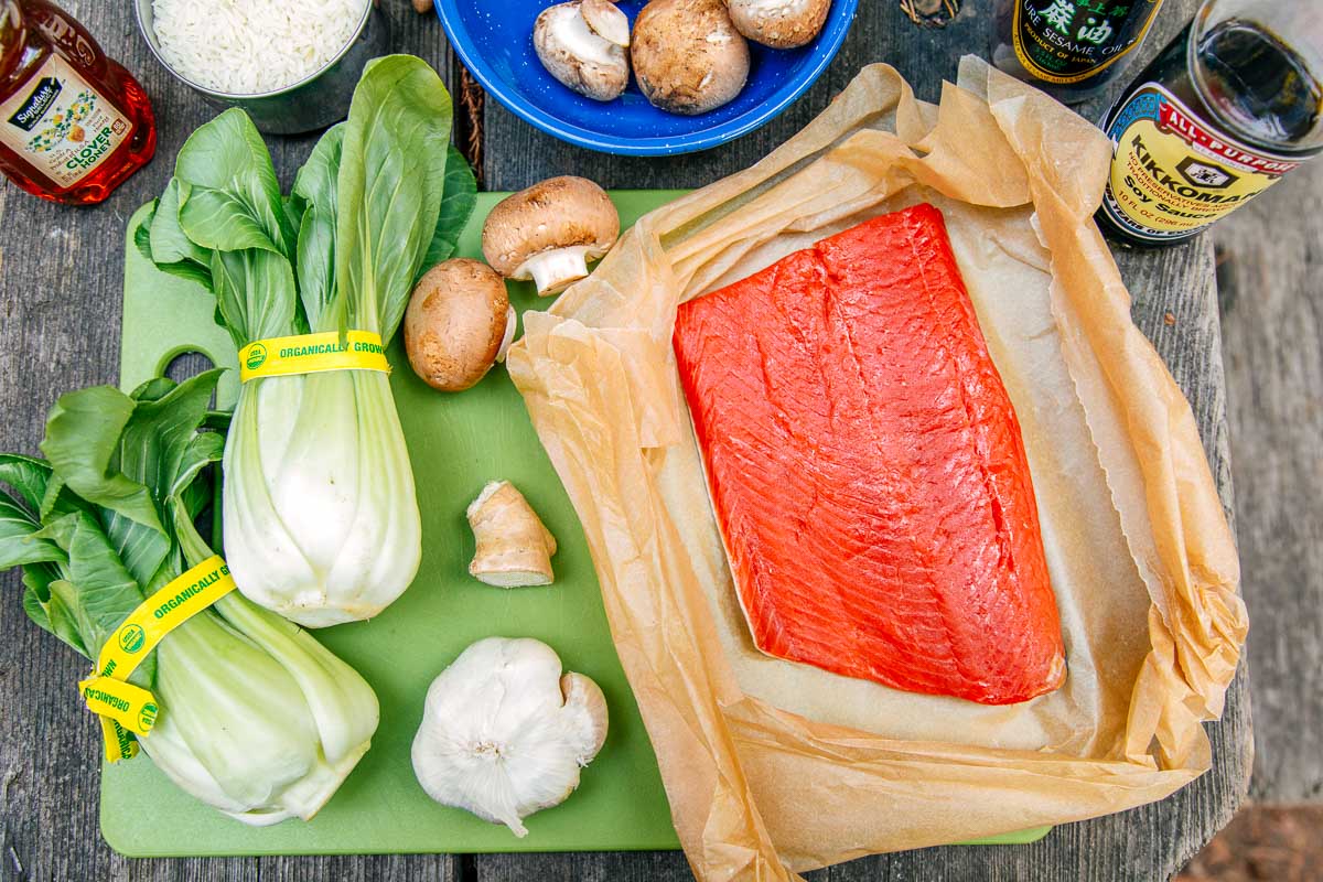 Ingredients for Honey Glazed Salmon on a cutting board: Salmon, bok choy, mushrooms, garlic, and ginger.
