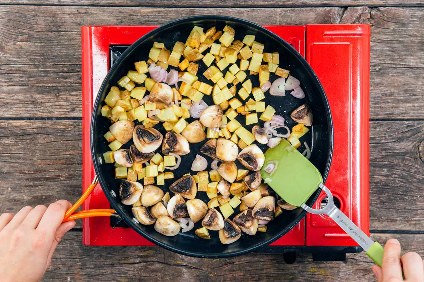 Sauteing cubed potatoes, quartered mushrooms, and shallots in a large skillet for a tofu scramble