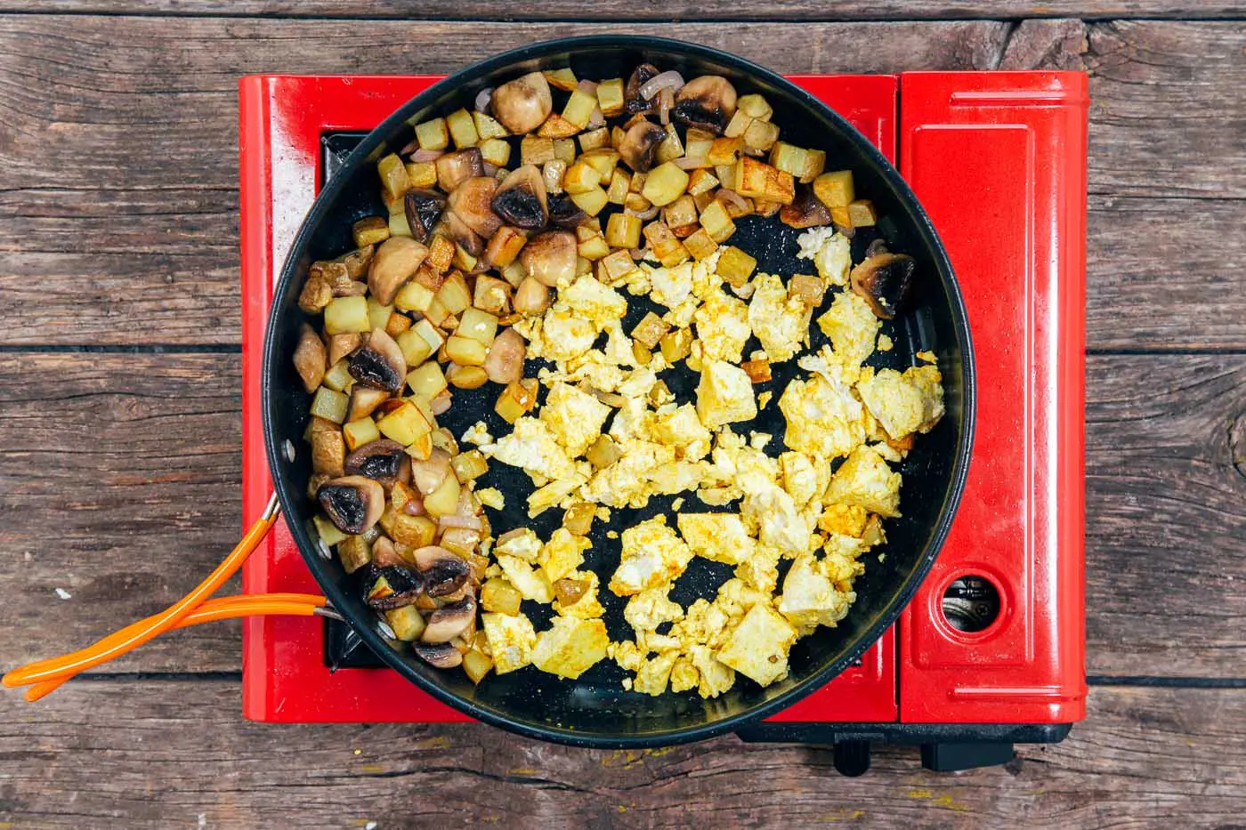 Cooking cubed potatoes and crumbled tofu in a large skillet for a scramble.
