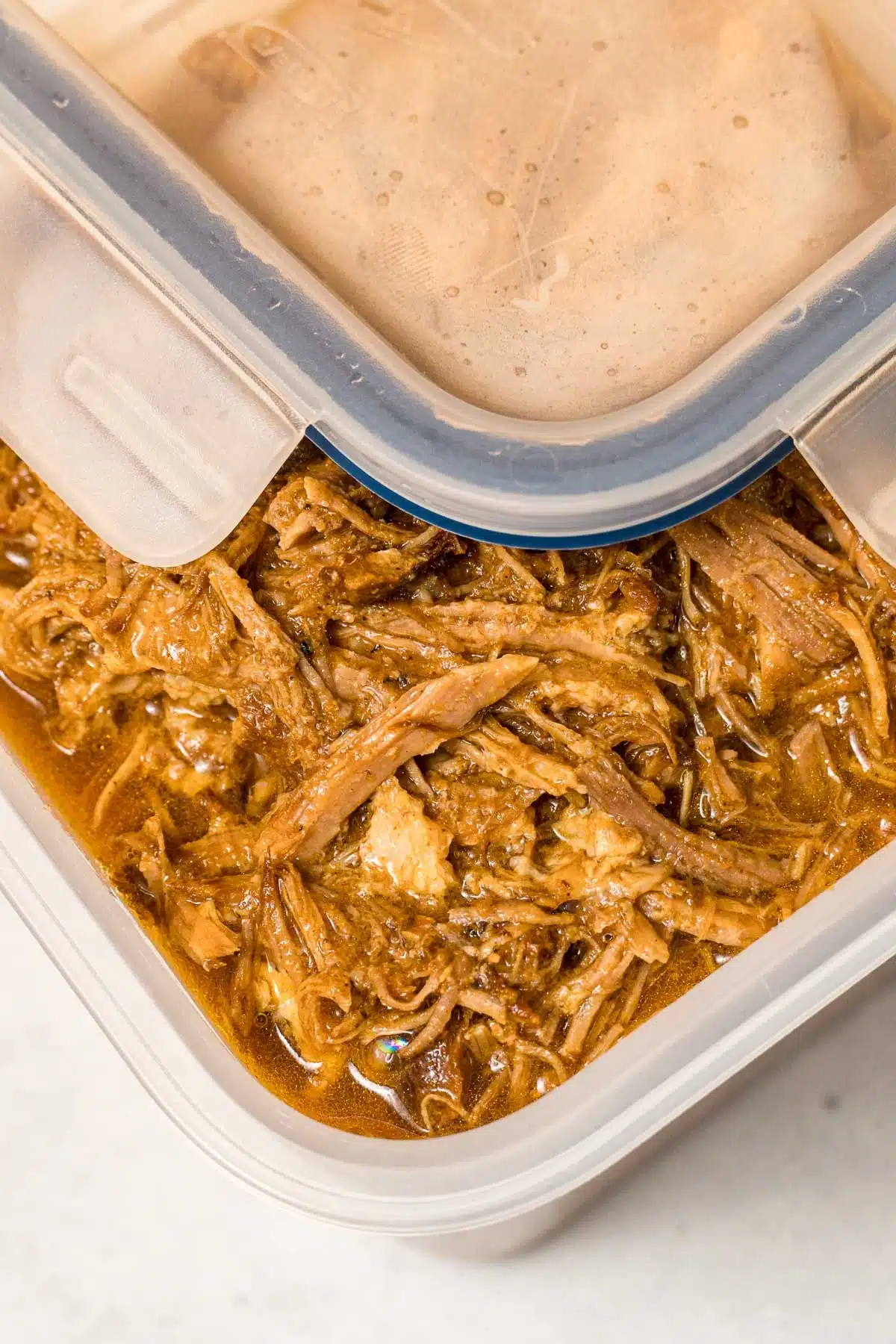 Pulled pork in a plastic storage container.