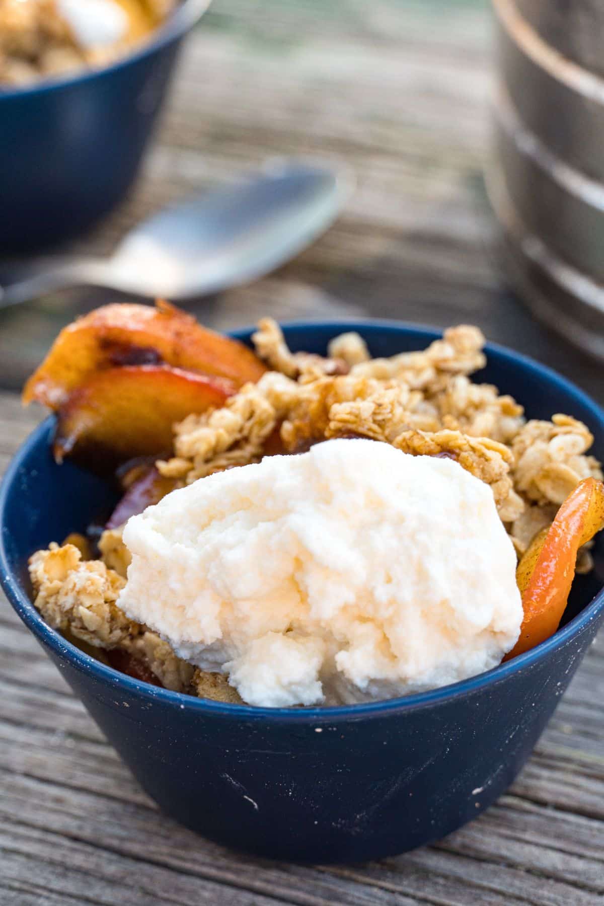 A scoop of ice cream in a small bowl with apple crisp.