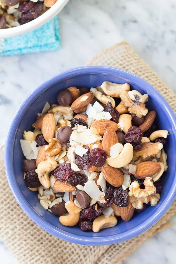 A bowl filled with a nutritious mix of almonds, cashews, walnuts, and raisins, sprinkled with coconut flakes - a healthy and tasty snack option.