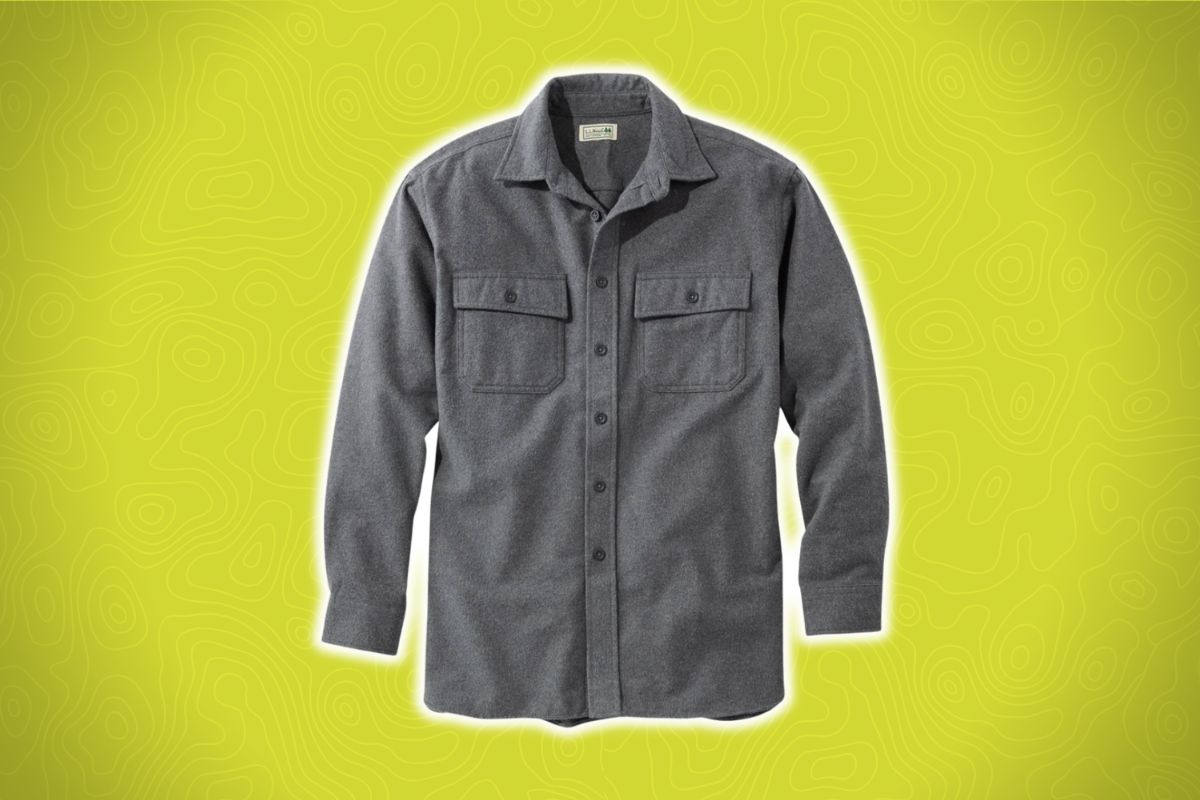 A long-sleeve gray flannel shirt with buttons and two chest pockets on a yellow background with a faint topographic pattern.