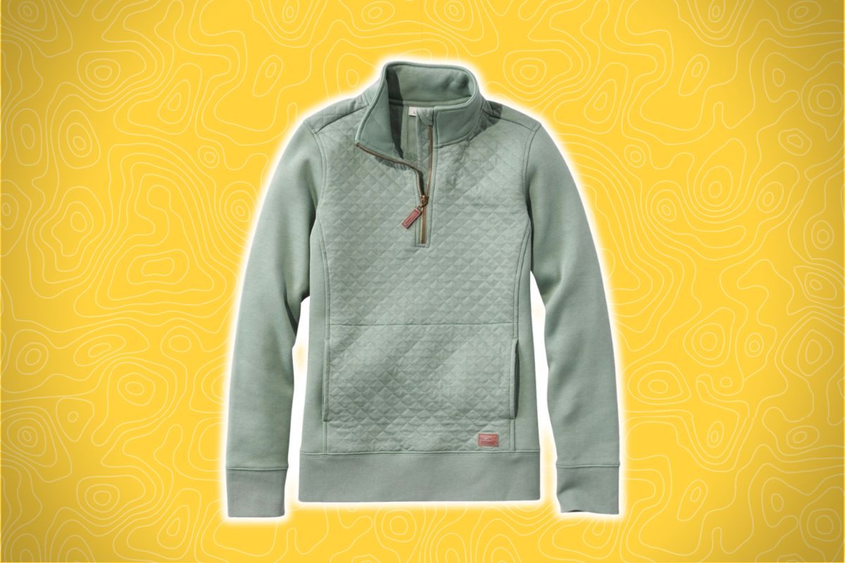 A light green quilted pullover with a quarter-zip collar and front pocket on a yellow textured background with swirling lines.