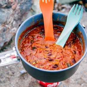 Lentil chili in a backpacking pot with two spoons