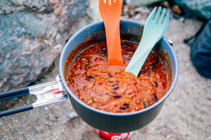 Lentil chili in a backpacking pot with two spoons