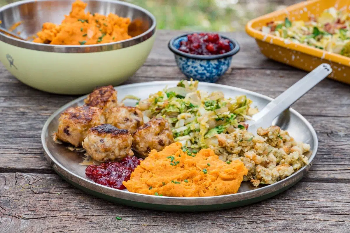 A plate with mashed sweet potatoes and other sides