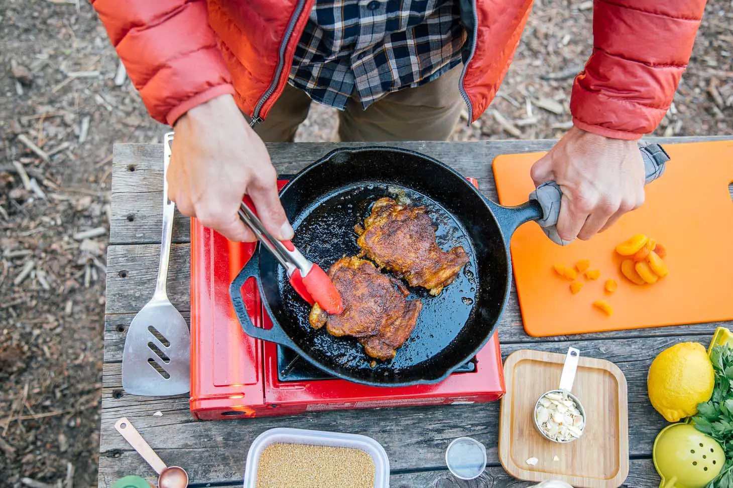 Michael cooking chicken in a cast-iron skillet over a camp stove