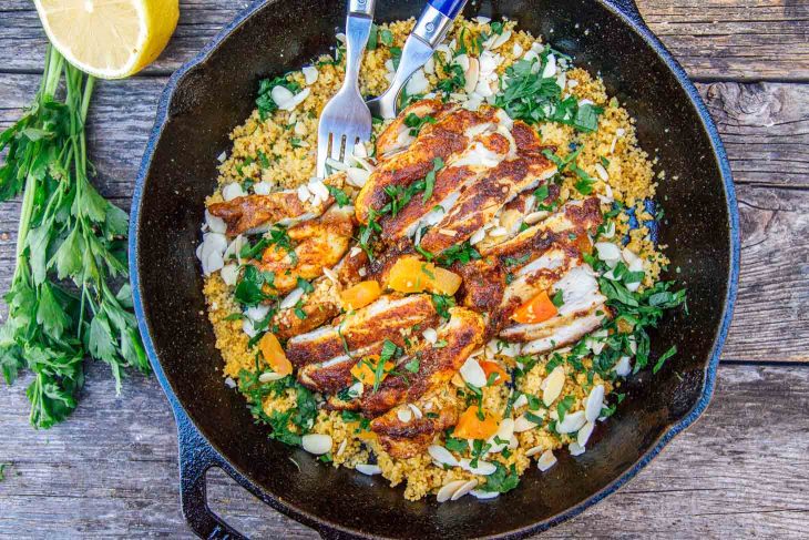 Chicken on a bed of couscous in a cast iron skillet on a camp table
