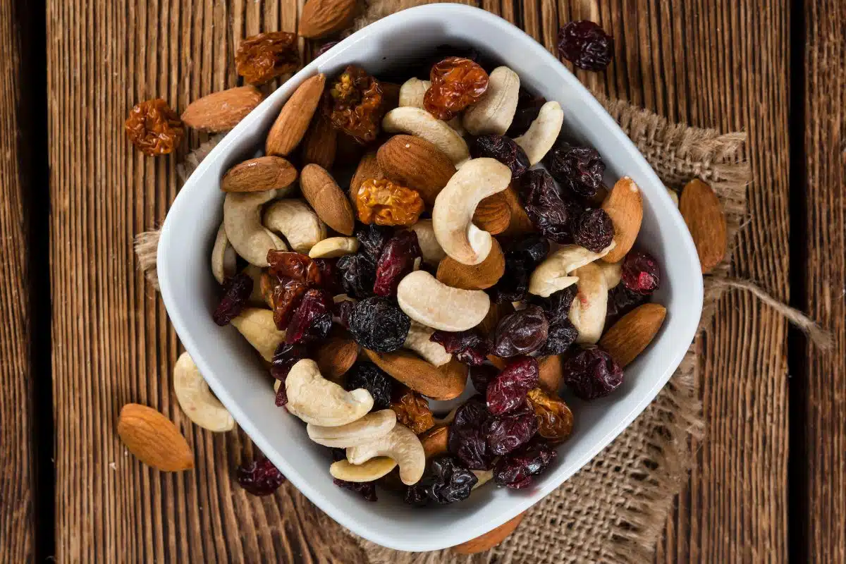 Mixed nuts in a bowl on a wood background.