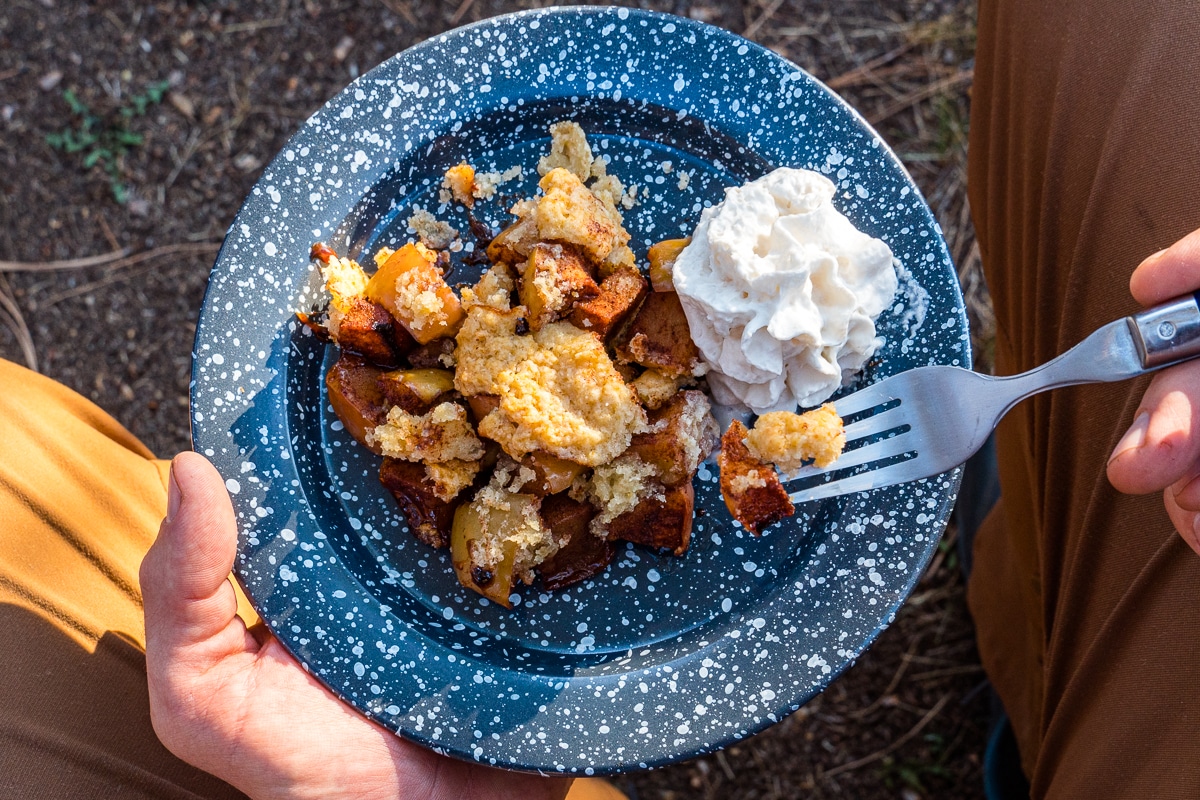 Apple cobbler on a blue plate with whipped cream