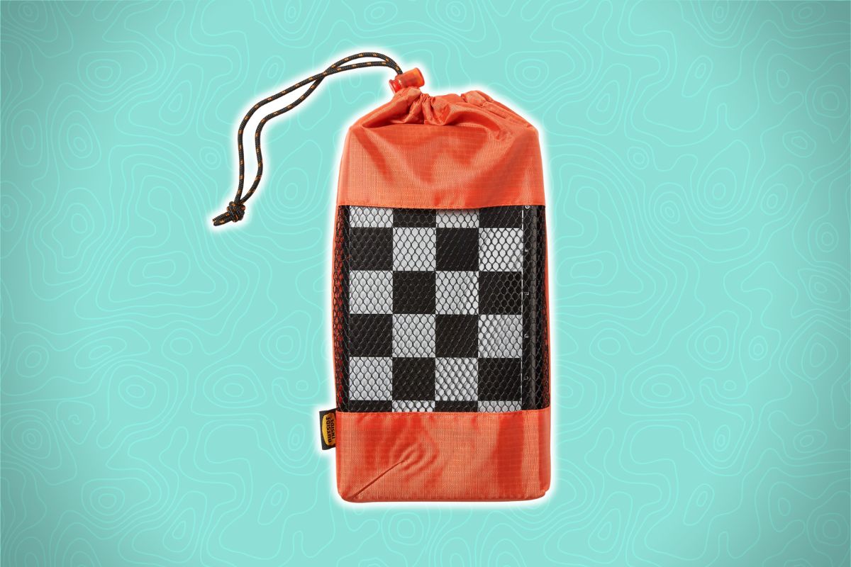 An orange drawstring bag with a black mesh window showing a checkerboard pattern, on a teal background with wavy lines.