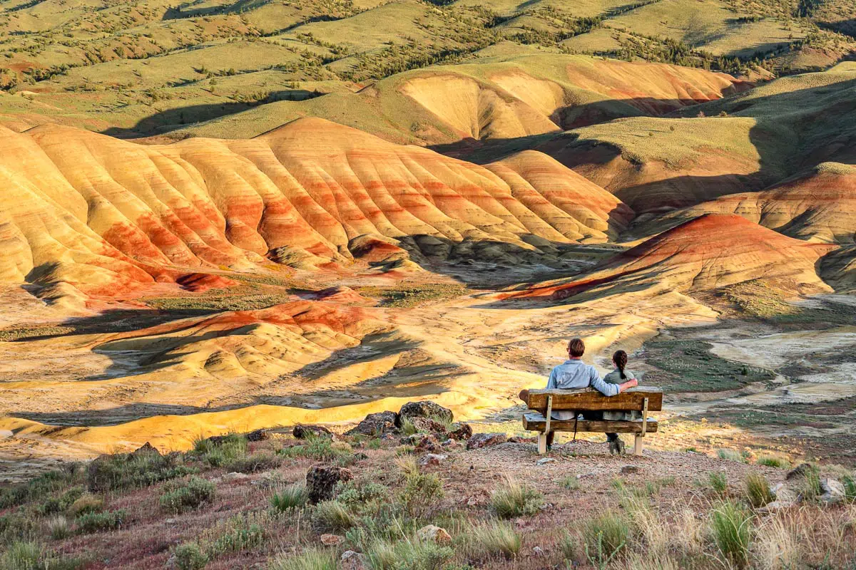 Megan and Michael sit on a bench looking out at the Painted Hills