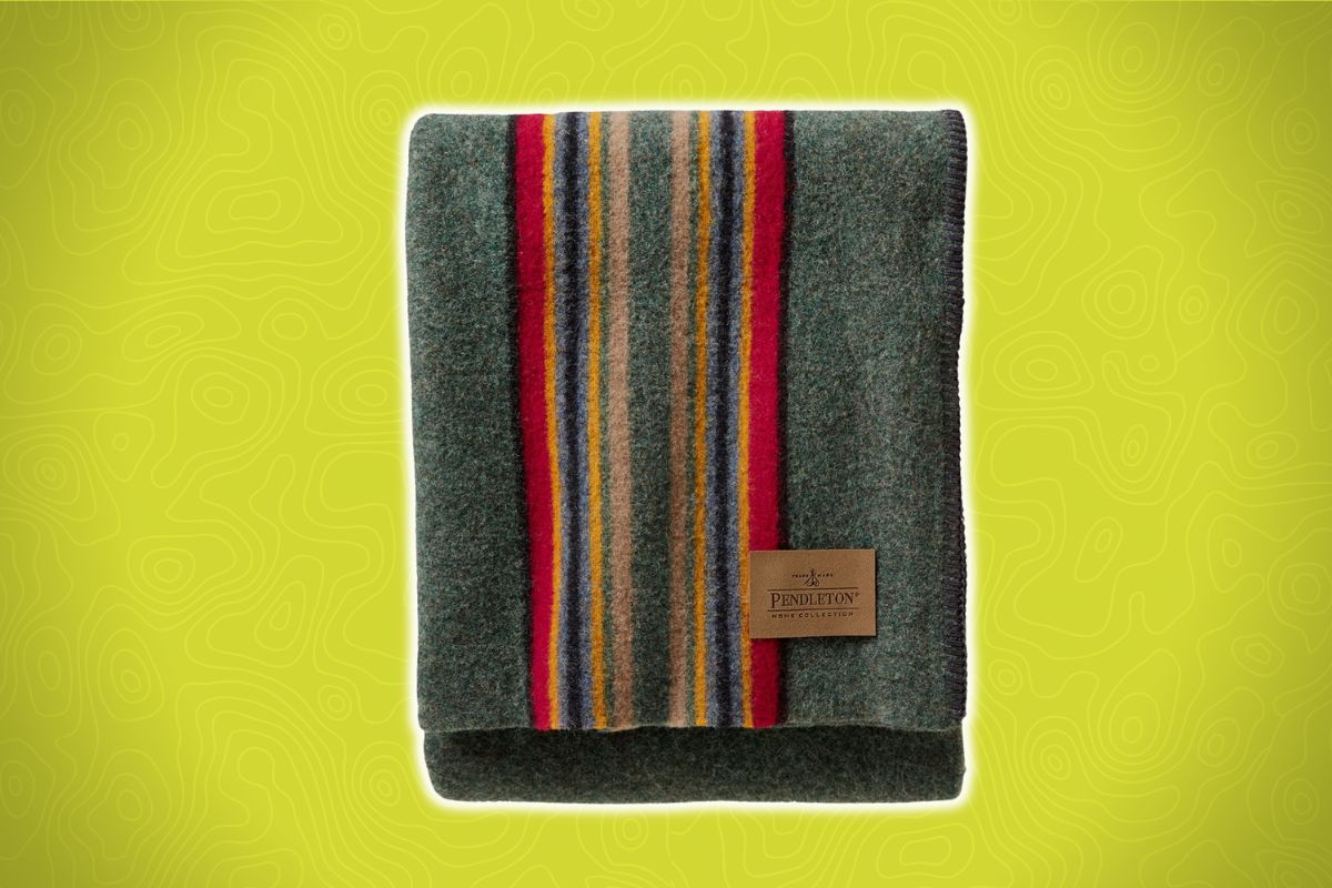 A folded wool blanket with vertical multicolored stripes and a brown Pendleton label on one corner, on a yellow patterned background.