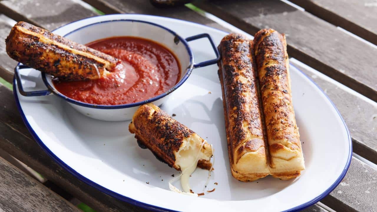 Mozzarella sticks on a plate with a small dish of red sauce.