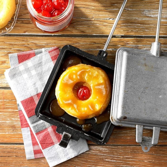 Bread, a pineapple ring, and a cherry in a pie iron.