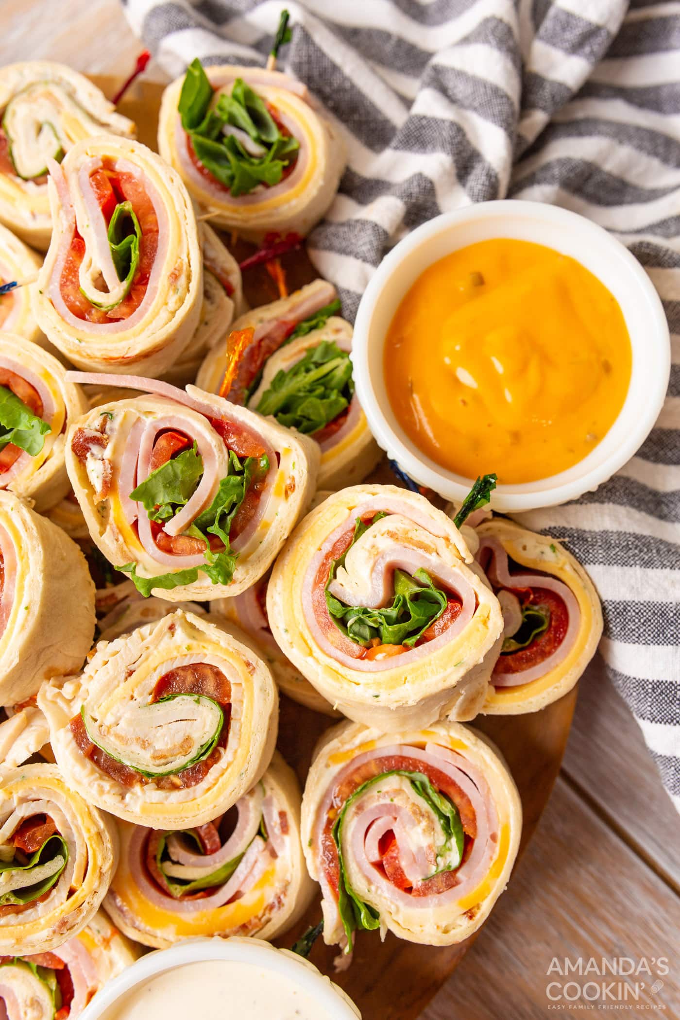 Pinwheel sandwiches on a wood background with a striped napkin.
