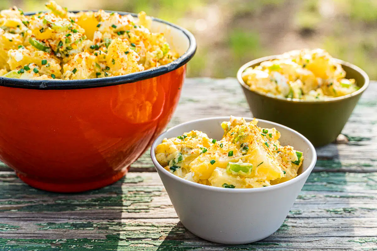 Two servings of potato salad next to a serving bowl
