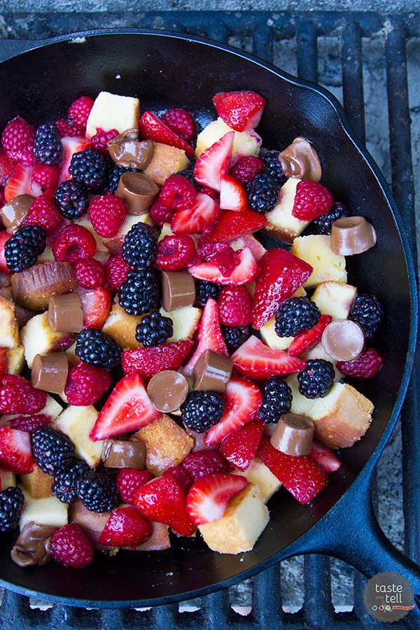 A skillet filled with squares of pound cake, strawberries raspberries and blackberries