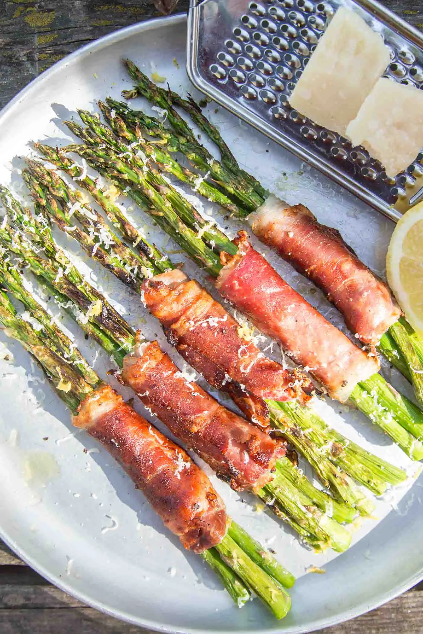 Five prosciutto wrapped asparagus bundles on a plate