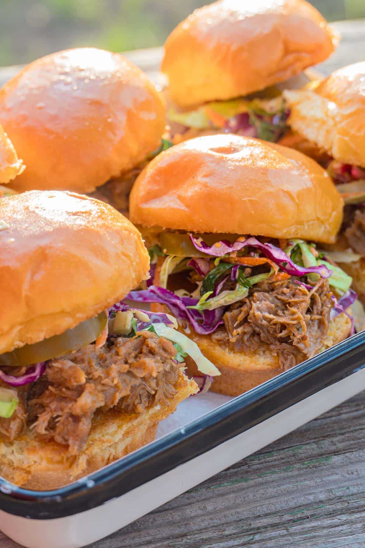 Pulled pork sliders arranged in a white dish.