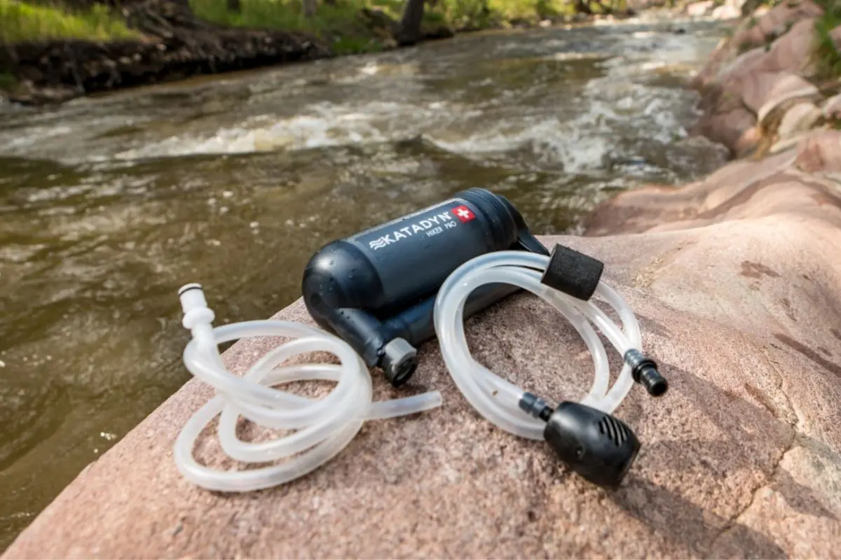 Katadyn Hiker Pump filter and tubes placed on a rock near a river