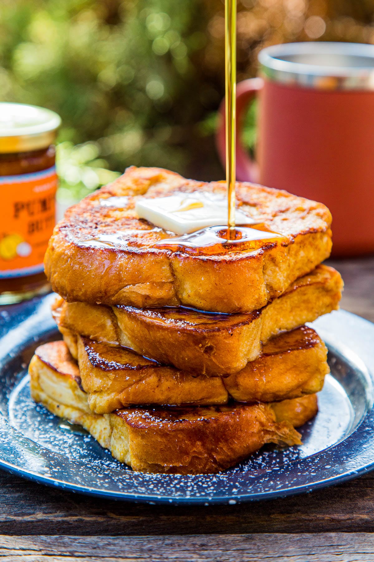 Four slices of pumpkin French toast stacked on a plate with a maple syrup drizzle
