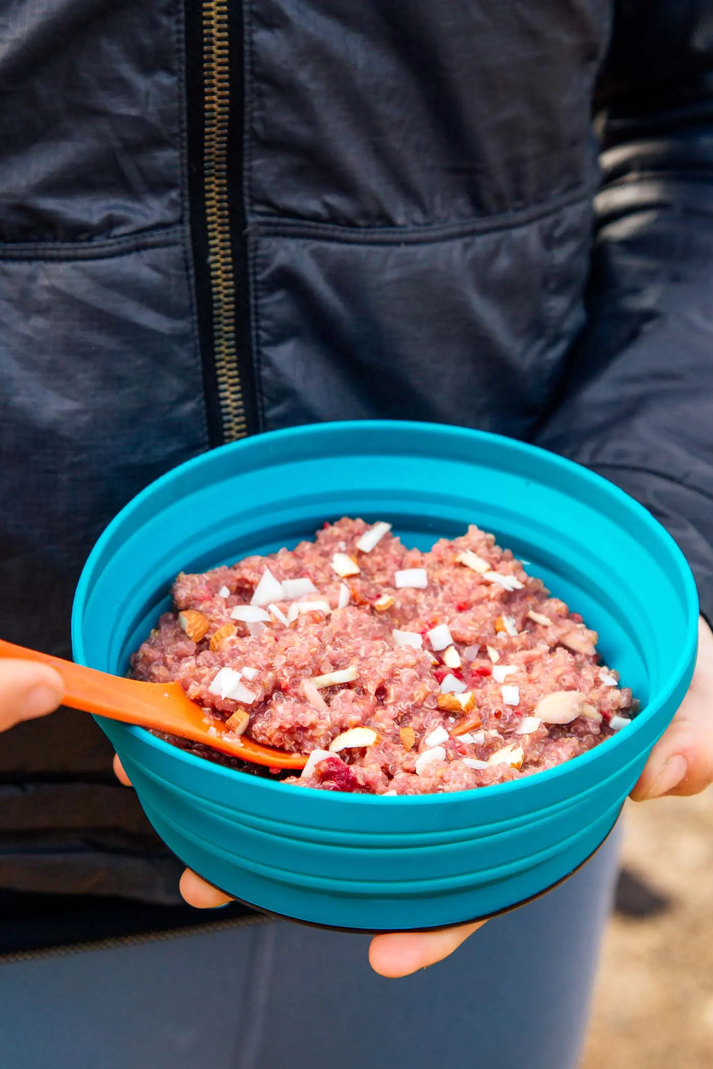 Woman holding a bowl of backpacking breakfast quinoa