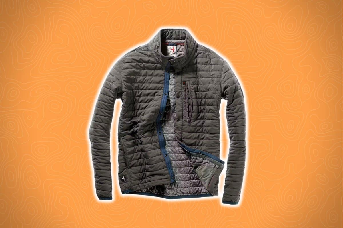 A gray quilted jacket with a partially open zipper reveals its contrasting interior lining against an orange, abstract patterned background.