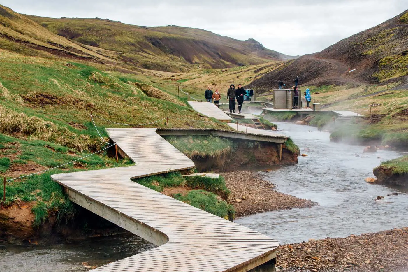 A wooden boardwalk winding around the Reykjadalur Hot Spring Thermal River