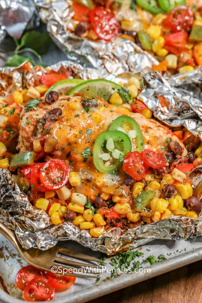 Chicken topped with melted cheese and vegetables in foil.