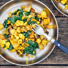 Overhead horizontal photo of a tofu scramble with spinach on a silver camping plate.