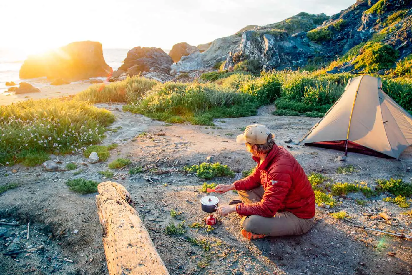 Man cooking over a backpacking stove on the beach