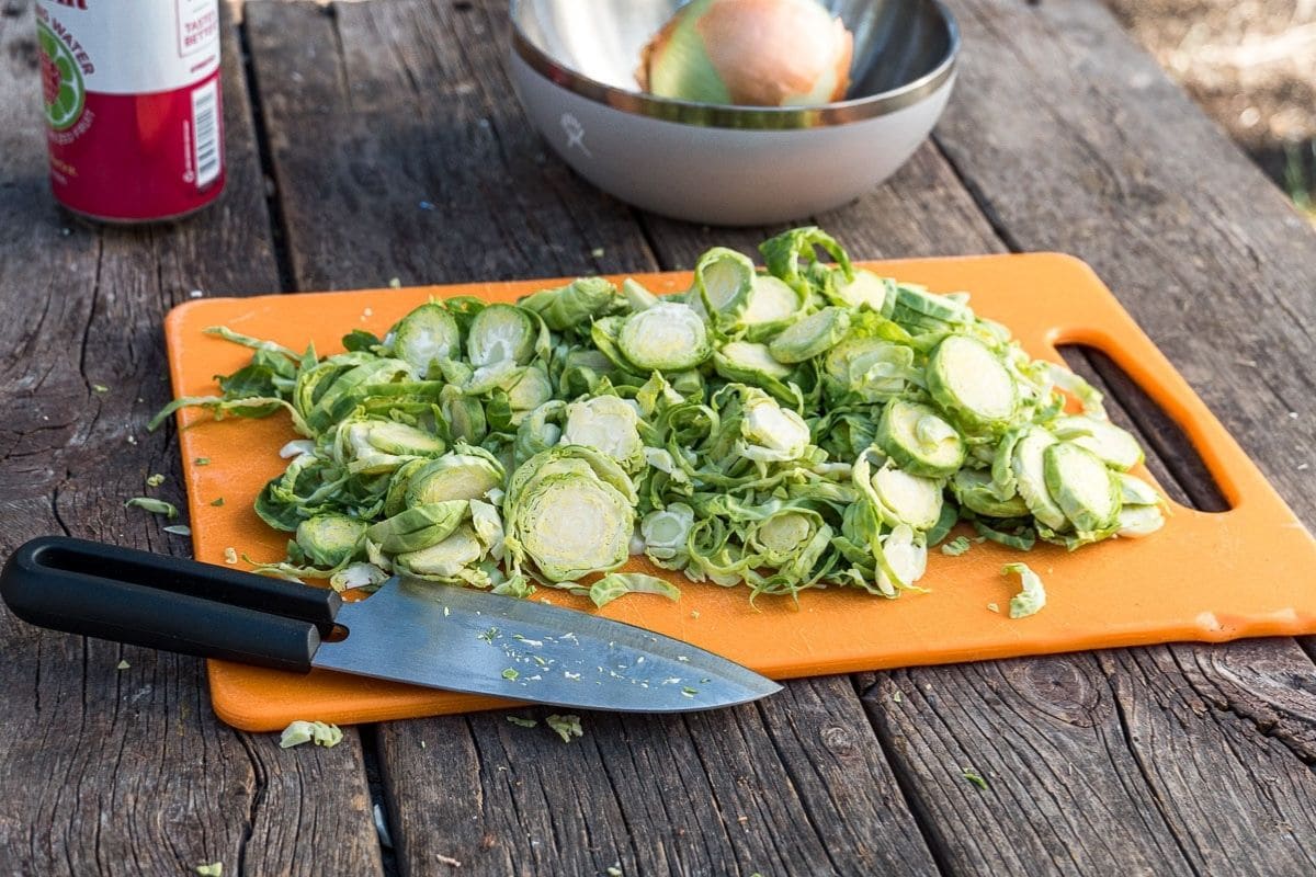 Shredded brussels sprouts on an orange cutting board