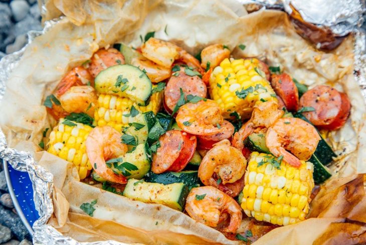 Close up of shrimp, corn on the cob, and sausage cooked in a foil packet