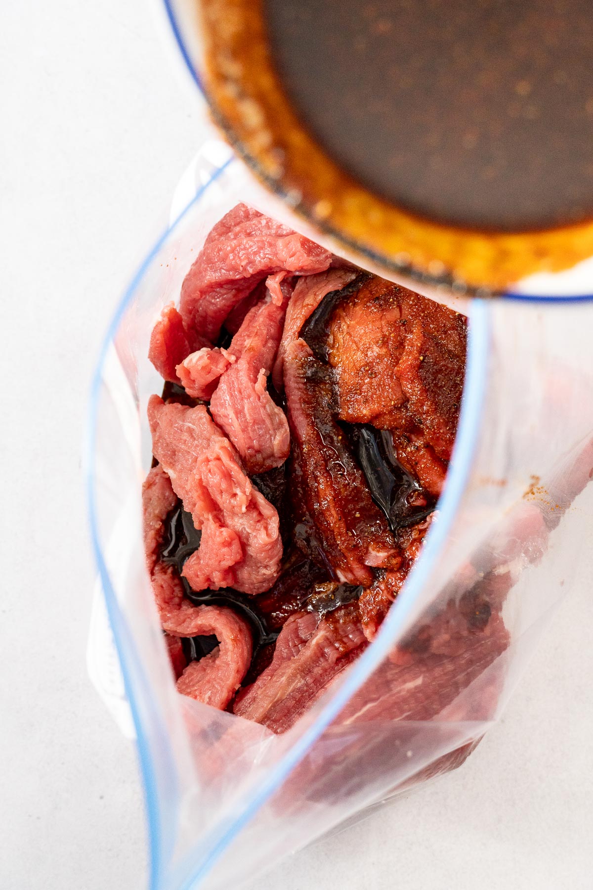 Pouring marinade over beef jerky in a bag