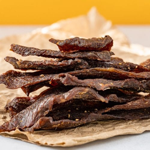 Beef jerky stacked on a piece of parchment paper