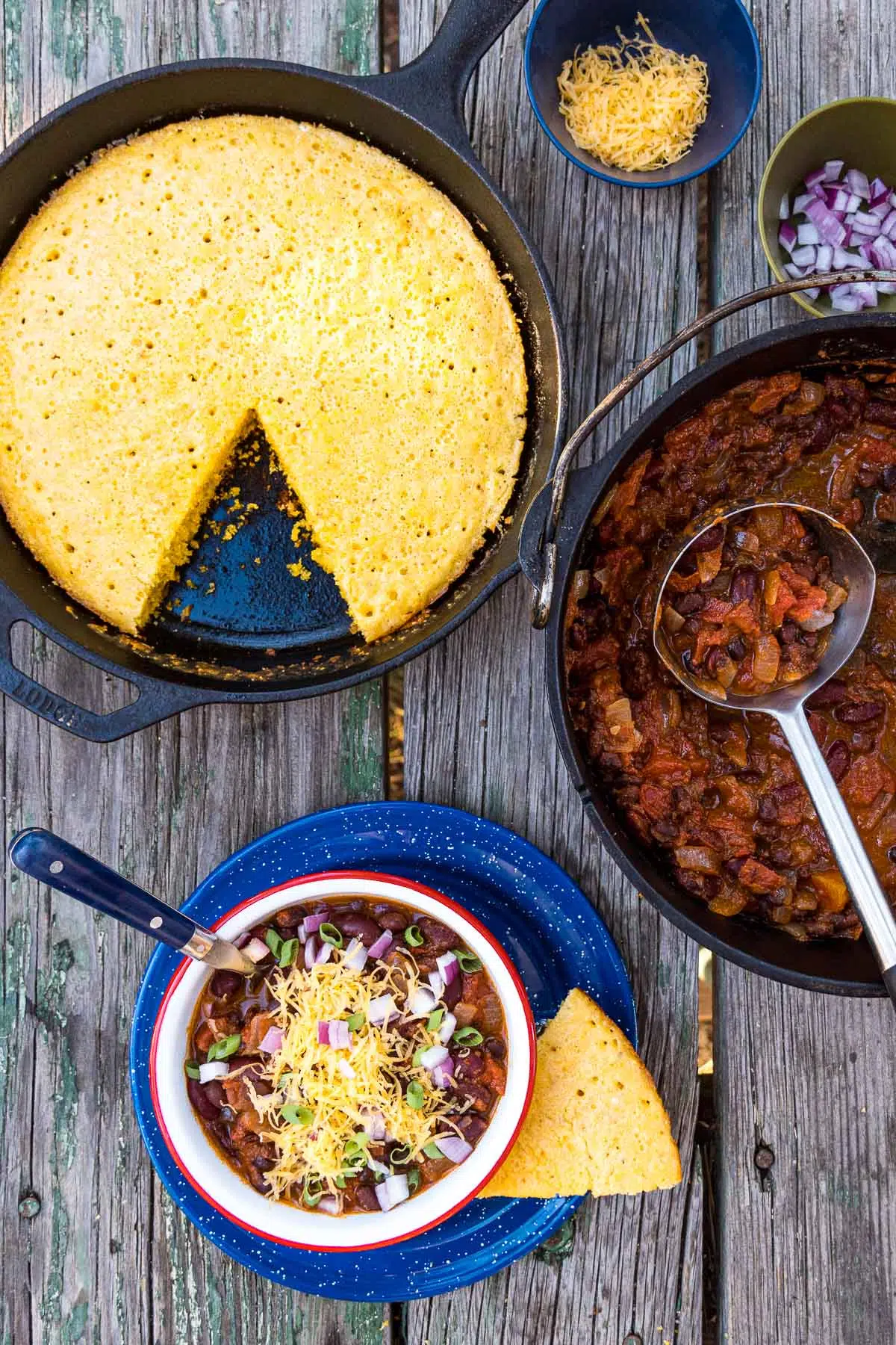 Cornbread in a skillet next to a bowl of chili with a slice of cornbread