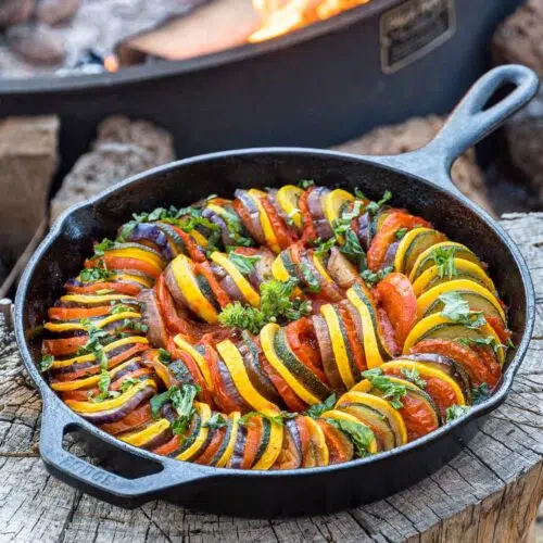 Ratatouille in a skillet with a campfire in the background