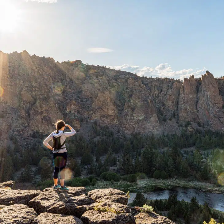 Megan standing at the edge of a trail overlooking a river and canyon walls
