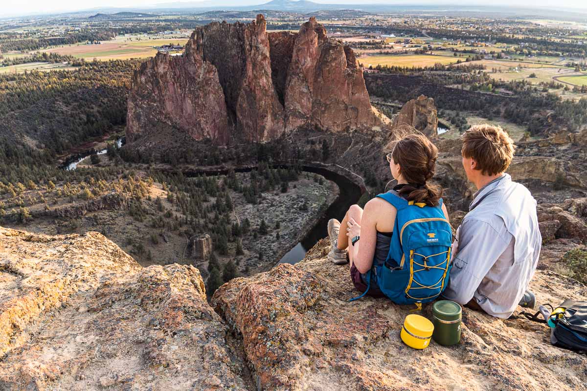 Megan and Michael sitting on a rocky overlook with Smith Rock in the distance