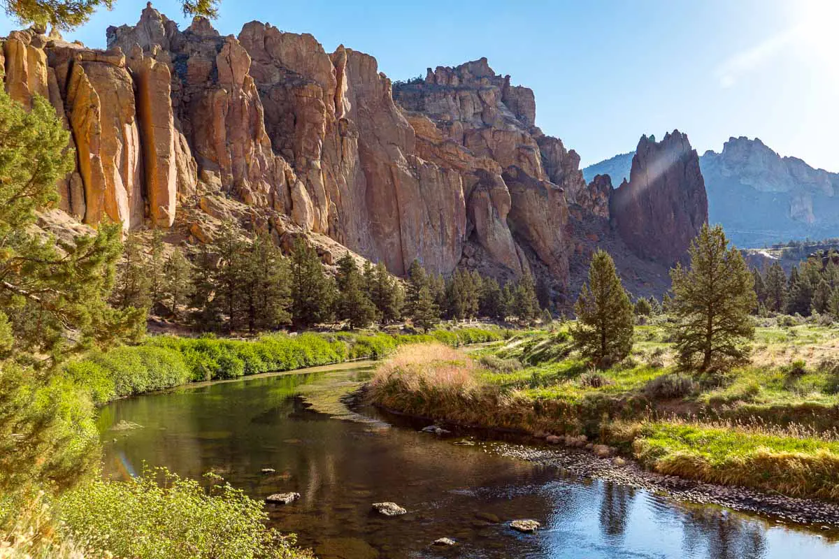 The Crooked River running through the canyon at Smith Rock State Park. Orange and red rocks make up the canyon walls.
