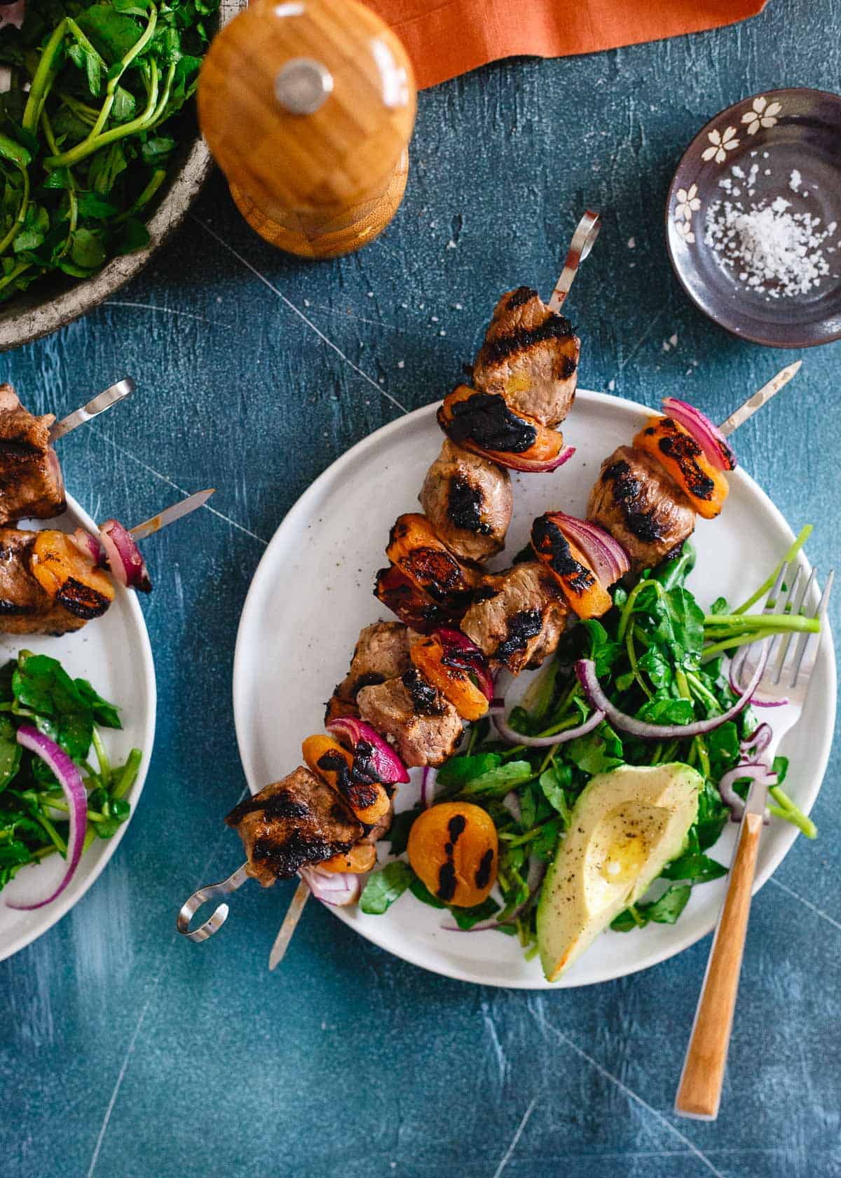 A plate of succulent grilled skewers with vegetables and a side salad, ready for a flavorful meal.