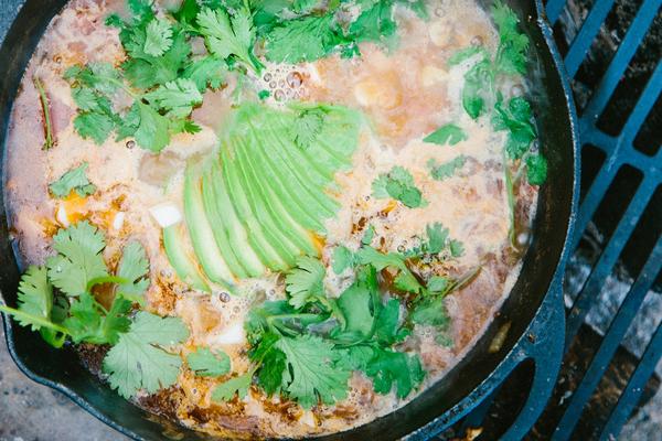 A dutch oven filled with sopa de lima, topped with avocado and cilantro