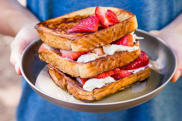 Michael holding a plate of stuffed french toast topped with strawberries