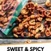 A bag of sweet and spicy trail mix spilled onto a rustic wooden surface, featuring an assortment of nuts and pretzels.