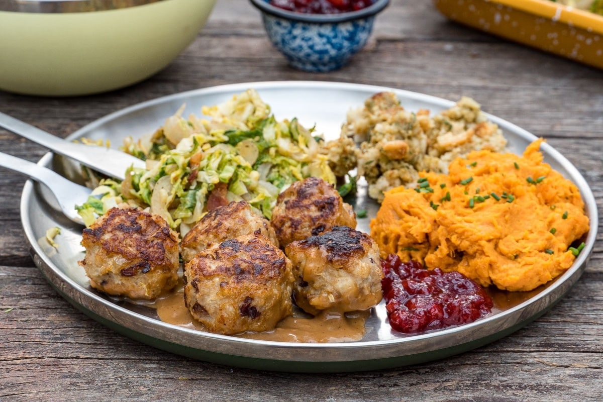 Turkey meatballs and gravy on a plate with colorful sides